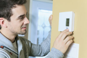 Man Adjusting Thermostat's Temperature